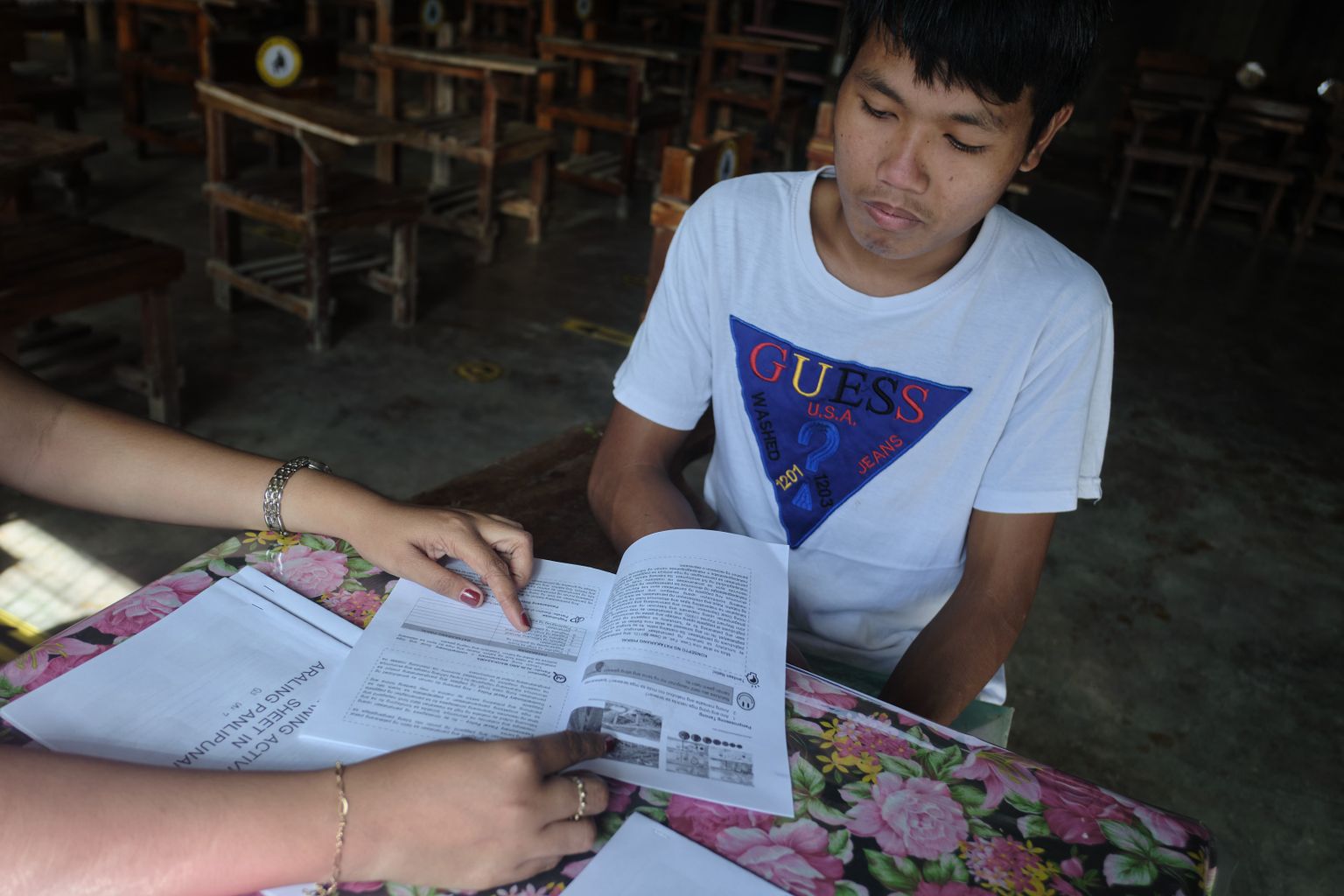 Eron’s teacher hands him his module. Eron goes to school only once a week as most schools in the Philippines remain closed from face-to-face classes due to the pandemic.