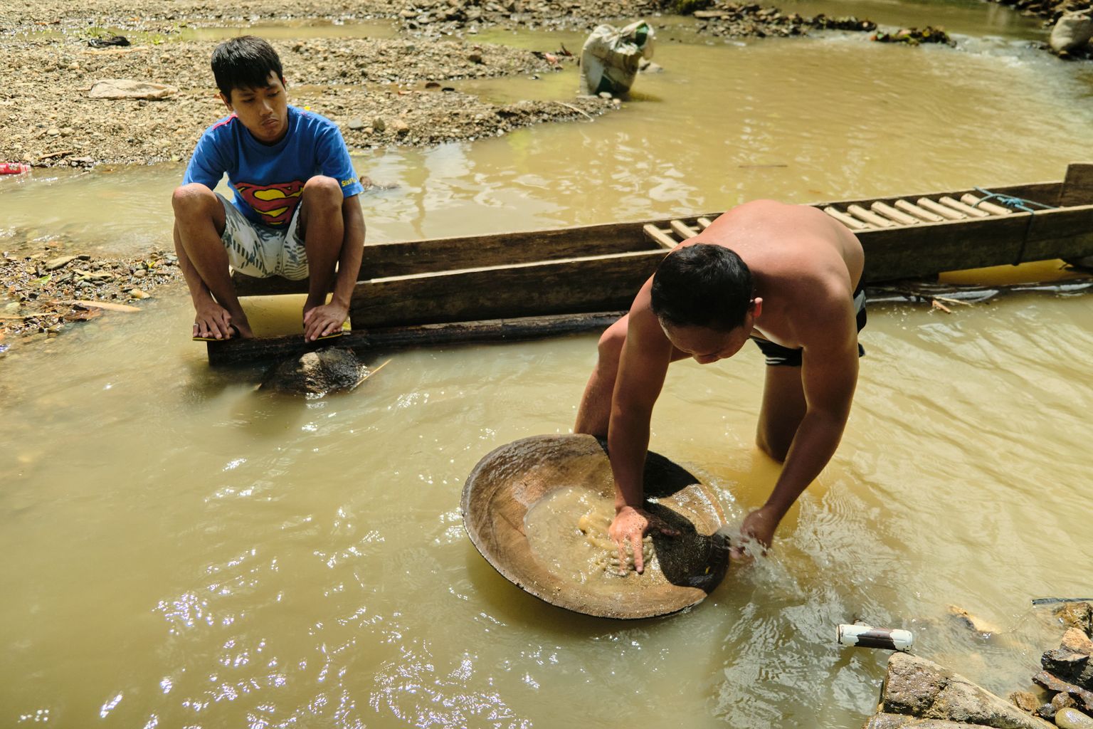 Eron talks to a miner in the river where he himself used to operate.