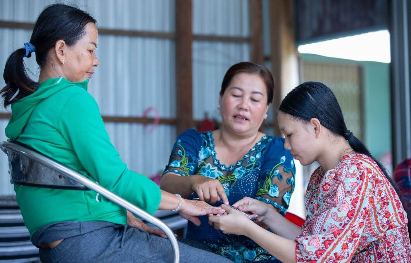 A salon owner (middle) guides Ngan on how to care for nails during her vocational training.
